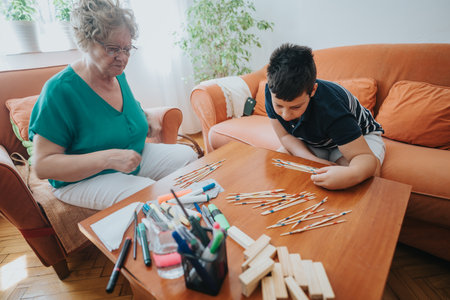 Young boy playing pick-up sticks with grandmother in cozy living room