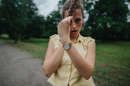Young woman in nature park pulling her hair and looking intense on a cloudy dayの写真素材