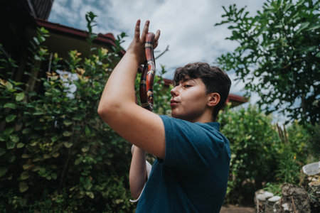 Young person enjoying playful interaction with colorful snake in gardenの写真素材