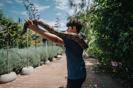 Girl confidently playing with a large snake in a garden setting