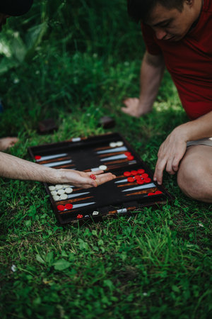 Two friends playing backgammon outdoors on a grassy fieldの写真素材