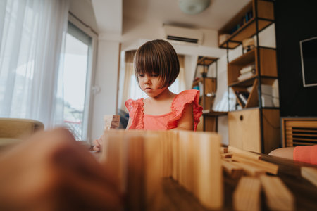 Young girl playing with wooden blocks in cozy modern apartmentの写真素材