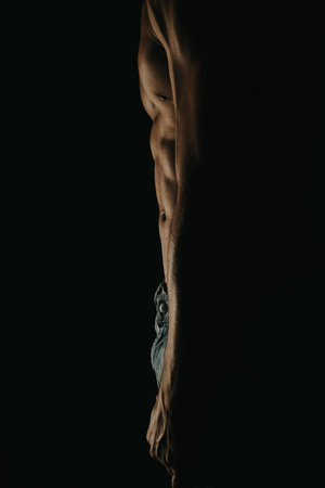 Muscular mans torso in low light, highlighting abs and muscle definitionの写真素材