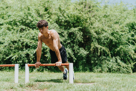 Fit young male athlete performing exercise outdoors in parkの写真素材