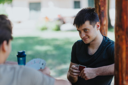 Young men playing cards in a relaxed outdoor setting