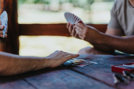 People playing card game at rustic outdoor tableの写真素材
