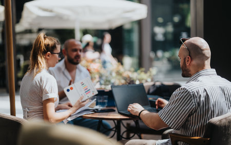 Startup team in business meeting discussing, brainstorming, analyzing and strategizing at an outdoor cafeの写真素材