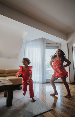 Joyful children in red dresses playing indoors together at homeの写真素材