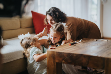 Mother and daughters playing and laughing in cozy living roomの写真素材