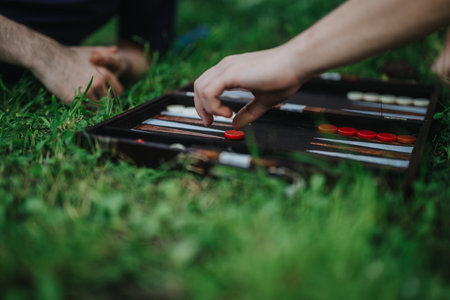 Hands playing backgammon outdoors on a grassy fieldの写真素材