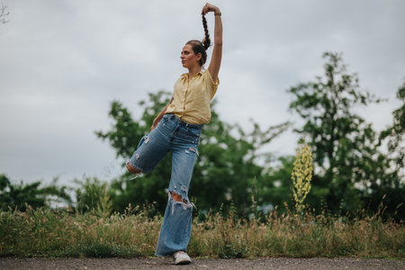 Girl having fun alone in the park while striking a playful poseの写真素材