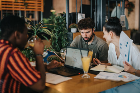 Diverse people collaborate in business meeting at a coffee bar with laptops and drinksの写真素材