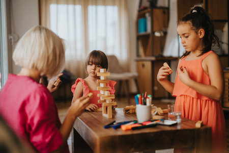 Children playing with building blocks at a wooden table indoorsの写真素材