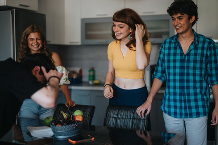 Group of friends laughing and enjoying time in kitchenの写真素材
