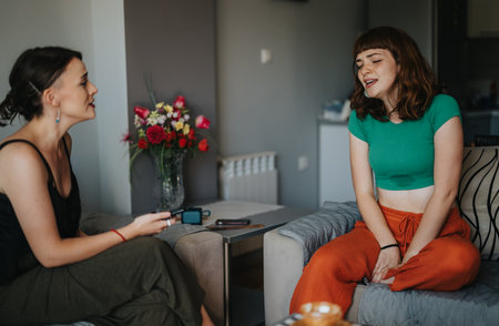 Two women enjoying a lively conversation in a cozy living roomの写真素材