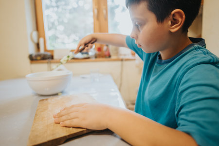 Young boy learning to cook in the kitchen by preparing ingredients