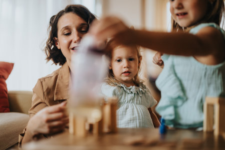 Mother playing with daughters at home with building blocksの写真素材