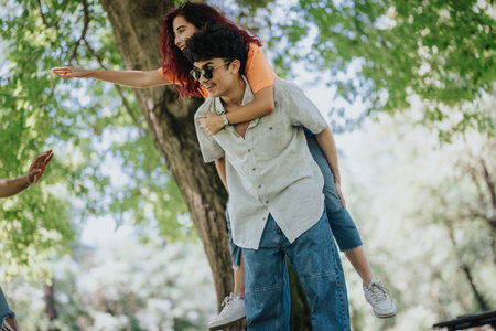 Young people enjoying a piggyback ride in a sunny park with lush green trees
