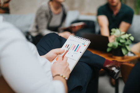 Young business entrepreneurs in an outdoor meeting discussing charts and data analysisの写真素材