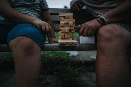 Two people playing a wooden block tower game outdoorsの写真素材