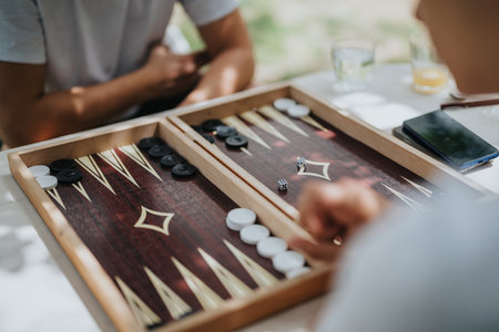 Friends playing backgammon together outdoors on a sunny day