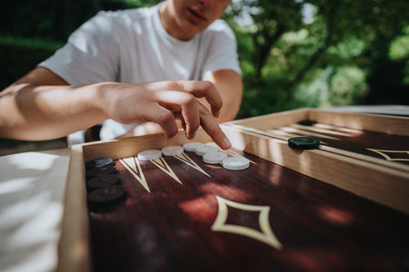 Person playing backgammon outdoors with natural sunlightの写真素材