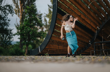 Happy young girl dancing outdoors in a stylish outfit with headphonesの写真素材