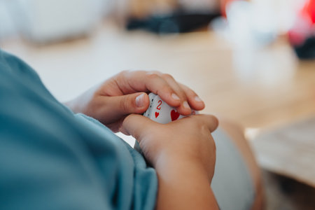 Child holding playing cards while having fun at home