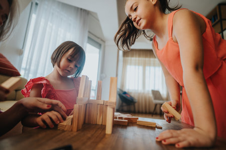 Girls playing with wooden blocks at home in casual settingの写真素材