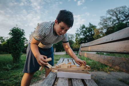 Young boy enjoying building block game on park benchの写真素材