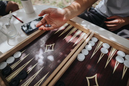Close up of a backgammon game with dice and players hand outdoors