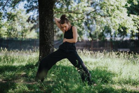 Young woman dancing gracefully in the park, performing modern dance moves