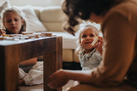 Mother playing with daughters in cozy living room settingの写真素材