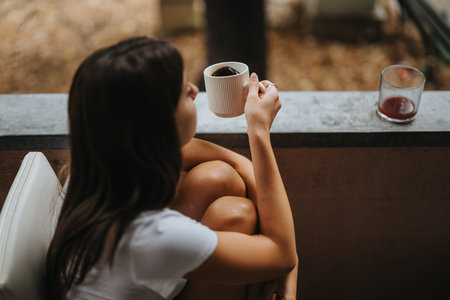 Woman enjoying coffee on a peaceful outdoor balcony settingの写真素材