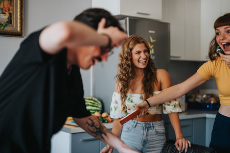 Friends enjoying a fun moment together in the kitchenの写真素材