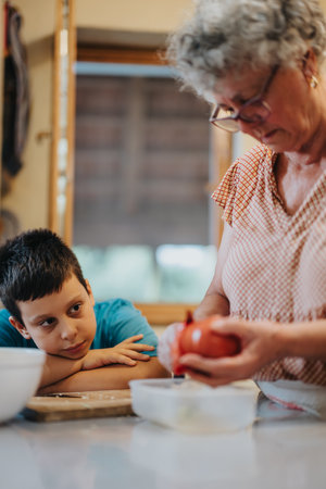 Grandmother teaching grandson how to cook in the kitchenの写真素材