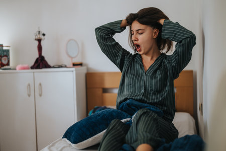 Woman in pajamas yawning and stretching in the morningの写真素材