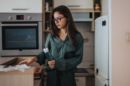 Young woman in kitchen preparing breakfast with a water bottleの写真素材