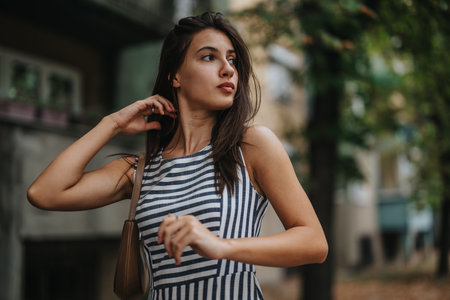 Young woman in striped dress outdoors looking thoughtfullyの写真素材
