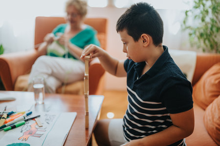 Grandmother knitting while nephew plays with building blocks at homeの写真素材