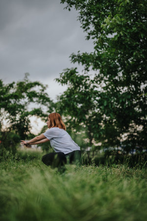 Woman practicing yoga in a lush green outdoor settingの写真素材