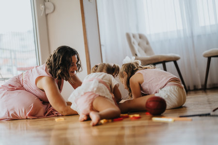 Mother and daughters playing together on the floor at home, bonding and spending quality timeの写真素材