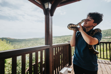 Young girl happily playing with pet snakes on a sunny day outdoorsの写真素材