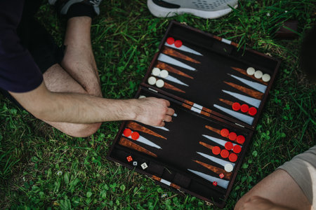 Friends playing backgammon outdoors on a sunny day in the parkの写真素材