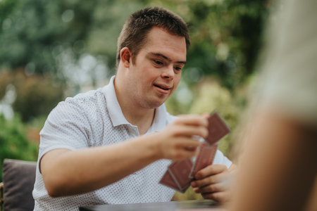Young man with disability playing cards outdoorsの写真素材