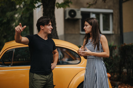 Young friends having a lively conversation by a vintage yellow carの写真素材