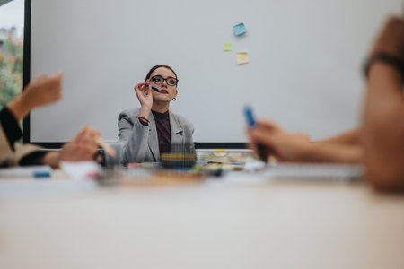 Focused businesswoman leading team brainstorm meeting in officeの写真素材