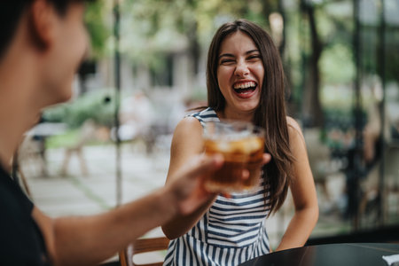Joyful friends laughing and toasting in an outdoor cafe setting
