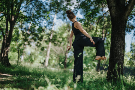 Lovely girl dancing in nature, female dancer performing modern dance in a serene forest settingの写真素材