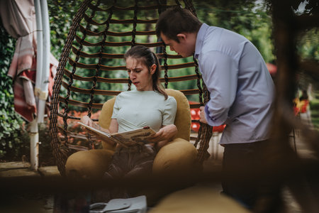 Boy with Down syndrome helps girl read a book outdoors